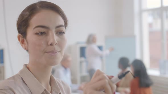 Portrait of Mixed-race Businesswoman Drawing on Glass Wall