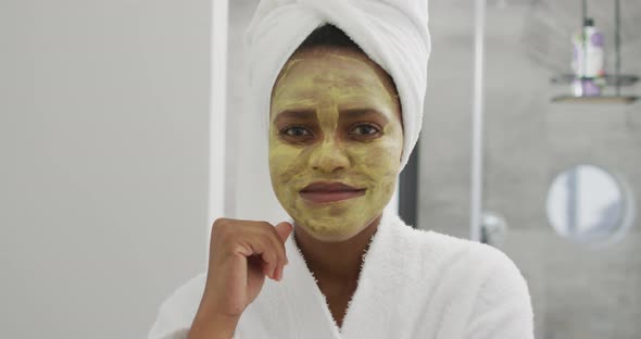 Portrait of happy african american woman with beauty mask on face, smiling in bathroom