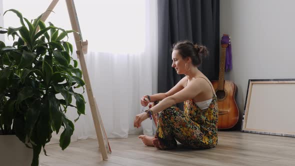 Charming woman paints a painting on canvas in atmospheric workshop.