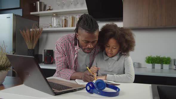 Loving Handsome Black Father Helping Adorable School Age Daughter to Do Homework at Home