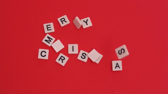 Letter tiles moving to spell merry christmas on red background