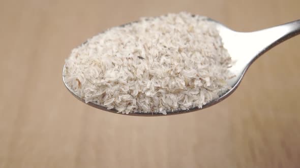 Psyllium husk pours from a metal dessert spoon