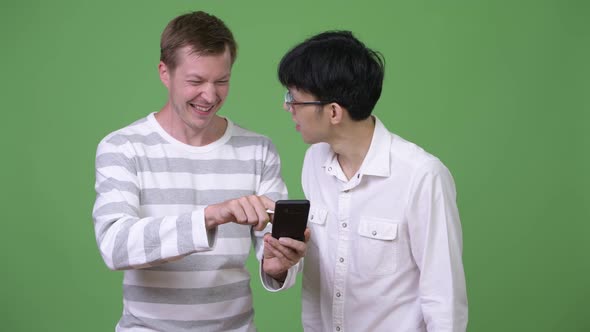 Two Happy Young Multi-ethnic Businessmen Using Phone Together