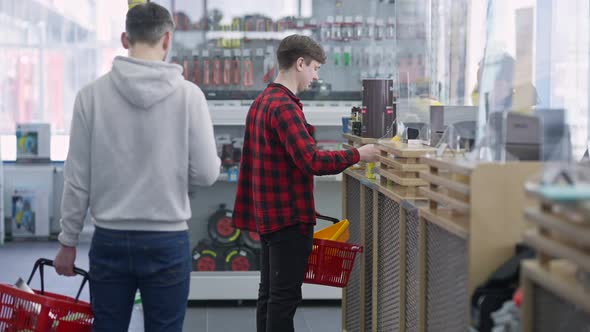 Side View of Young Male Customer Buying Goods at Cashier in Hardware Store