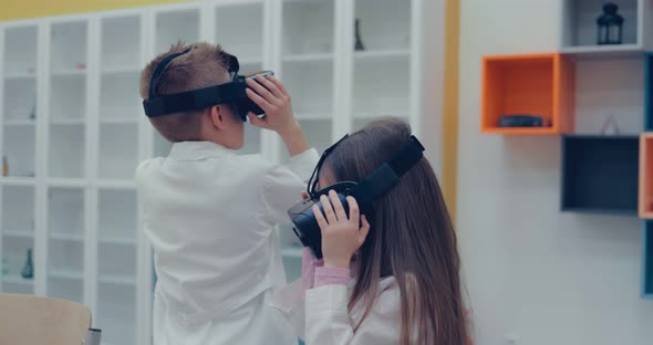 Little Boy and Little Girl in Virtual Reality Headset Standing in Classroom and Looking