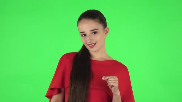 Portrait of Pretty Young Woman Is Smiling and Showing Heart with Fingers. Green Screen