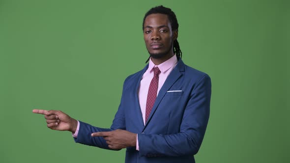 Young Handsome African Businessman with Dreadlocks Against Green Background