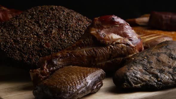 Rotating shot of a variety of delicious, premium smoked meats on a wooden cutting board 