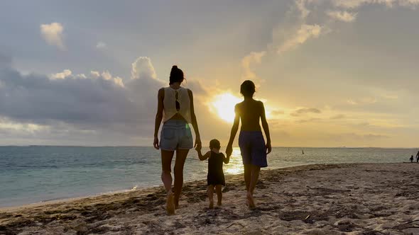 Happy Cheerful Family Walking on the Beach at a Beautiful Sunset