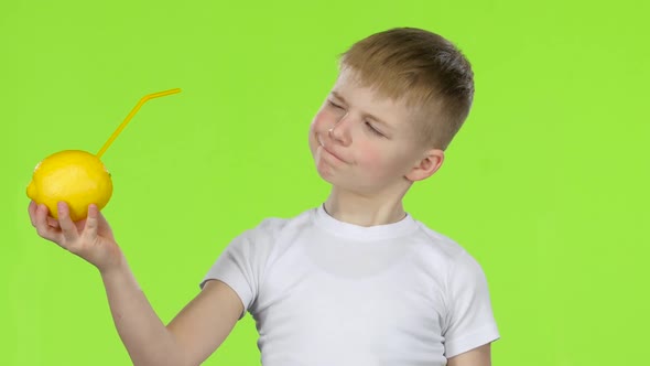 Kid Holds a Lemon Through a Straw Drinking Lemon Juice, and Shows a Thumbs Up. Green Screen