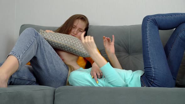 Charming European women lying on the couch fool around and laugh.