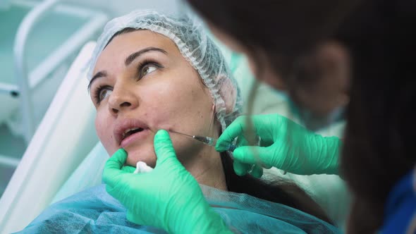 Woman Inserts Needle Under Client Skin for Filler Injection