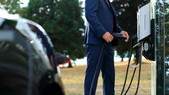 Businessman charging electric car at charging station 4k