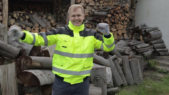 Lumberjack in Reflective Jacket. Man Woodcutter Dancing, Celebrate. Sawn Logs, Firewood Background