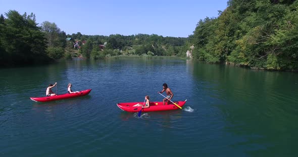 Four young friends paddling canoe and splashing each other with water