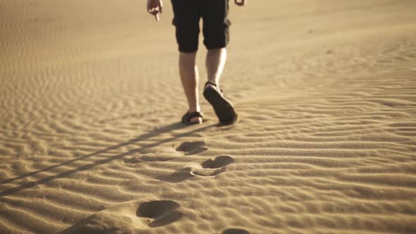 Man With Backpack Walking In Sand In Desert