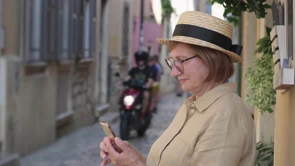 Mature Woman with Mobile in the Town Street