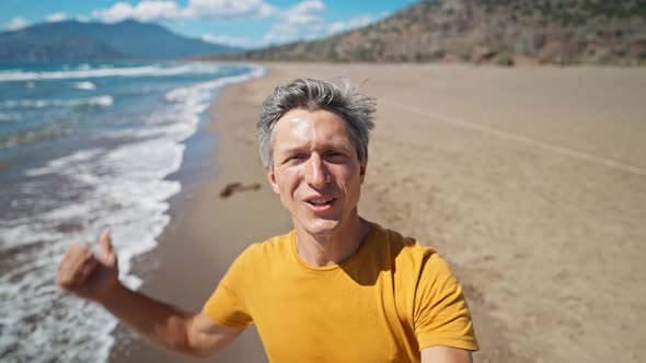 Close Up Selfie Portrait of Happy Middle Aged Greyhead Man at Sea Coast Enjoys Sunny Day on