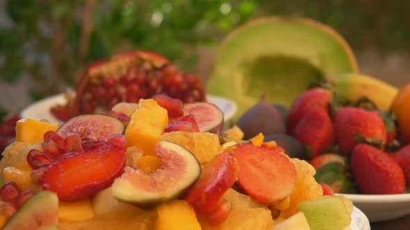 Closeup of the Pomegranate Seeds Falling on the Fruit Salad Made of Mango Figs