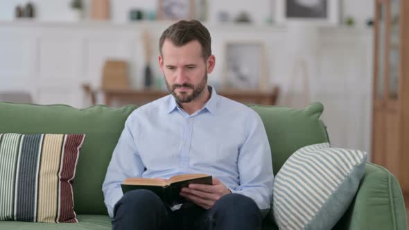 Young Man Reading Book at Home