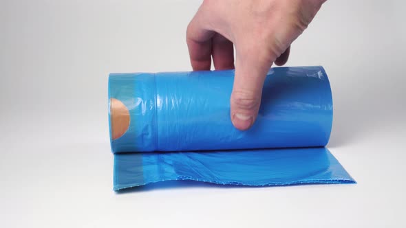 Hand puts blue roll of trash plastic recycled bags 