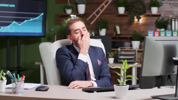 Exhausted Office Worker Yawning While Typing on the Computer