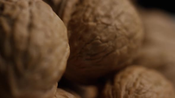 Cinematic, rotating shot of walnuts in their shells on a white surface - WALNUTS