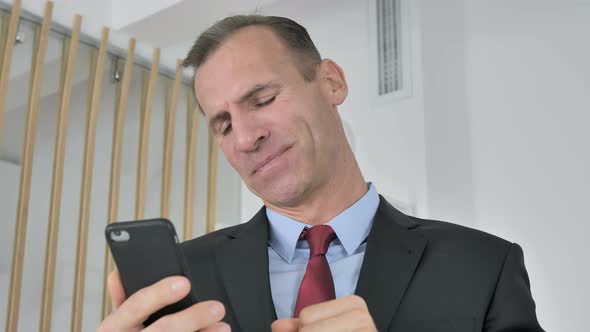 Tense Upset Middle Aged Businessman Reacting To Loss on Smartphone