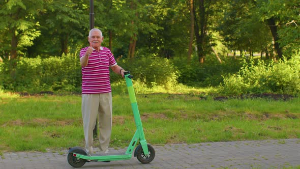 Senior Stylish Man Grandfather Riding Electric Scooter in Park Modern Grandpa Driving Urban Vehicle