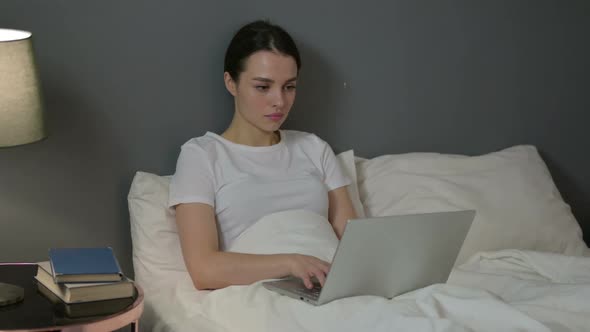 Professional Young Woman Working on Laptop in Bed