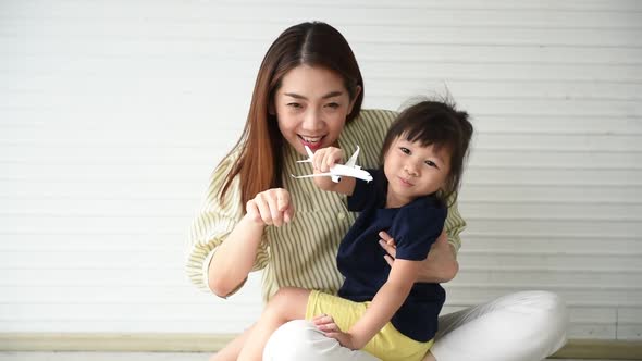 mother and daughters is 3-year-old, are plying airplane model