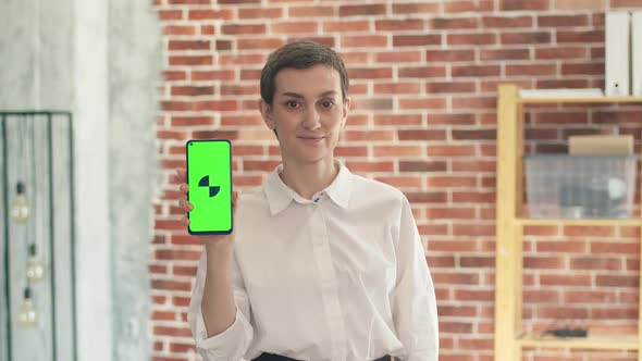 Cute Business Woman a White Shirt Holds a Phone with an App and Looks at the Camera While Standing