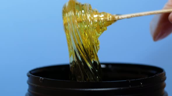 Sugar paste or honey wax for hair removal, dripping from wooden wax sticks - depilation and beauty