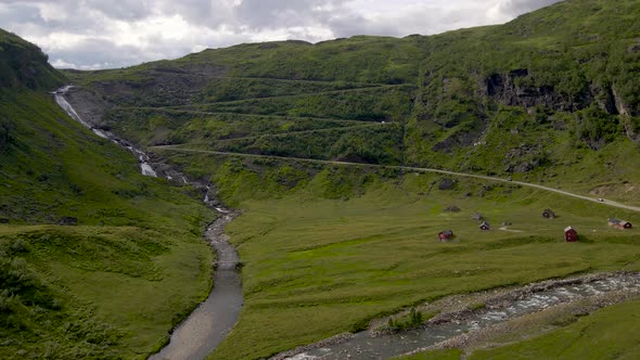 Aerial view of car driving on a narrow mountain pass road. Scenic natural landscape with waterfall a