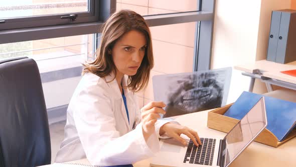 Doctor checking a x-ray while using laptop