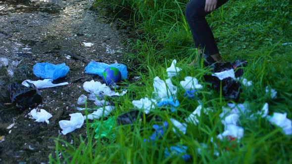 Woman Taking Earth Globe From Polluted Lake in Forest, Waste Recycling Problem