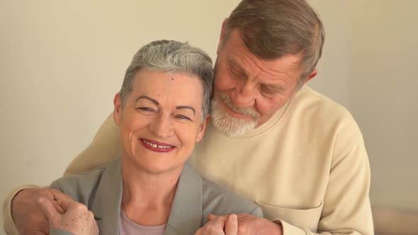 Close Portrait of Smiling Elderly Husband and Wife Looking at Camera