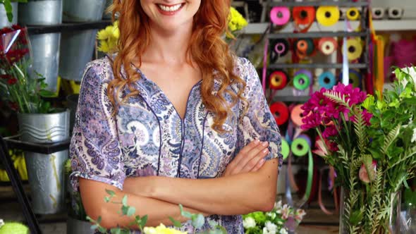 Happy female florist standing with arms crossed in flower shop