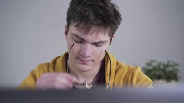 Close-up Portrait of Exhausted Caucasian Boy Taking Off Eyeglasses and Rubbing Eyes. Serious