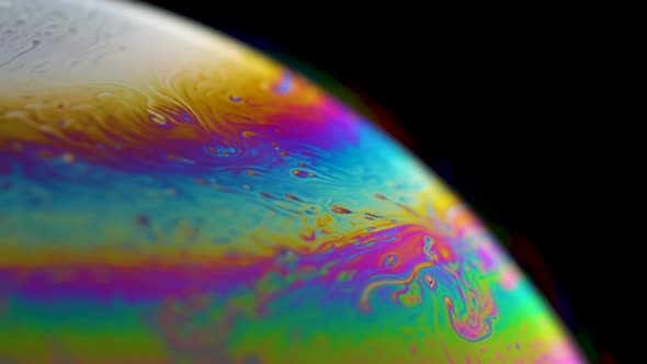 Macro shot of a soap bubble creates a colorful and psychedelic background. Rainbow colors