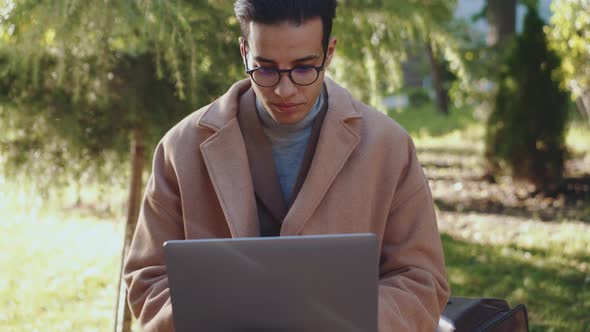 Smiling Arabian man working with laptop