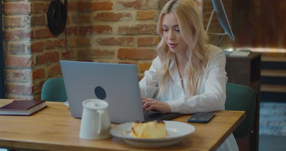 Young Woman Looking Busy Working on a Laptop at a Cafe