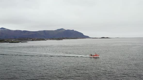 Small Boat Sailing Across The Atlantic Ocean In Averoy, Norway On A Cloudy Day. aerial orbit