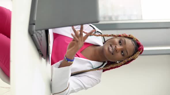Young African American Woman Doctor with Red Hair Having Chat or Consultation on Laptop
