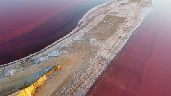 Aerial view of the top of the spit of the salt shore on a pink salt lake.