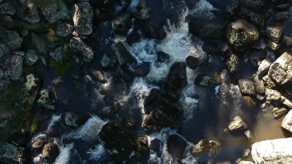 Low flying aerial of river flowing over rocks. Ebor falls, Australia