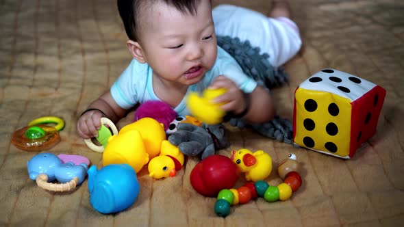 Chinese baby lay at bed chew the toy