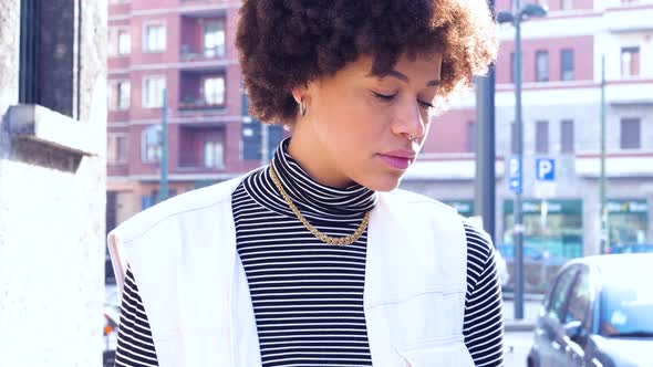 Slow motion portrait of young beautiful curly hair black woman outdoor in the city smiling healthy