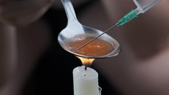 Preparing a Dose of Heroin in a Spoon Over a Candle Flame