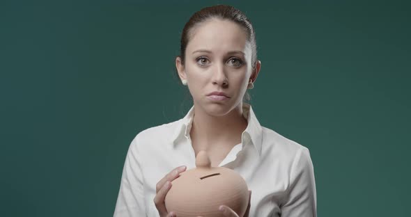 Disappointed young woman holding an empty money box, debts and financial loss concept